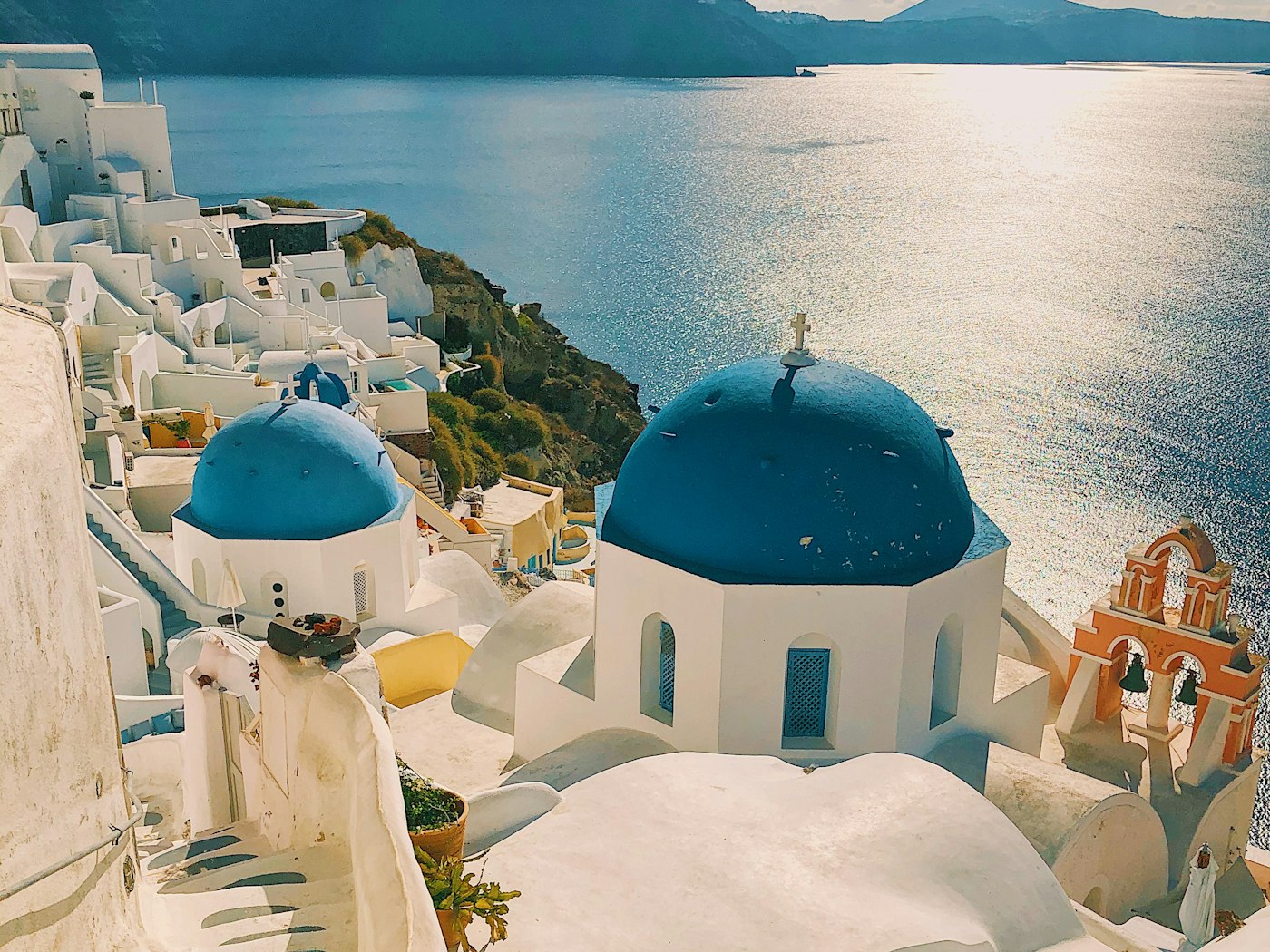 Blue-domed churches stepping down the white cliffs of Santorini above a bright sea.