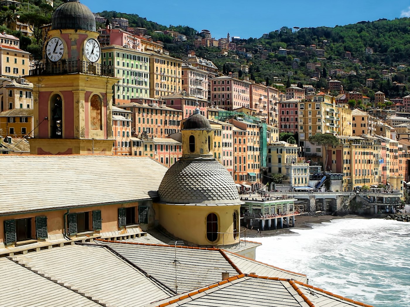 The pastel houses and clock tower of Camogli stacked above the sea on the Italian Riviera.