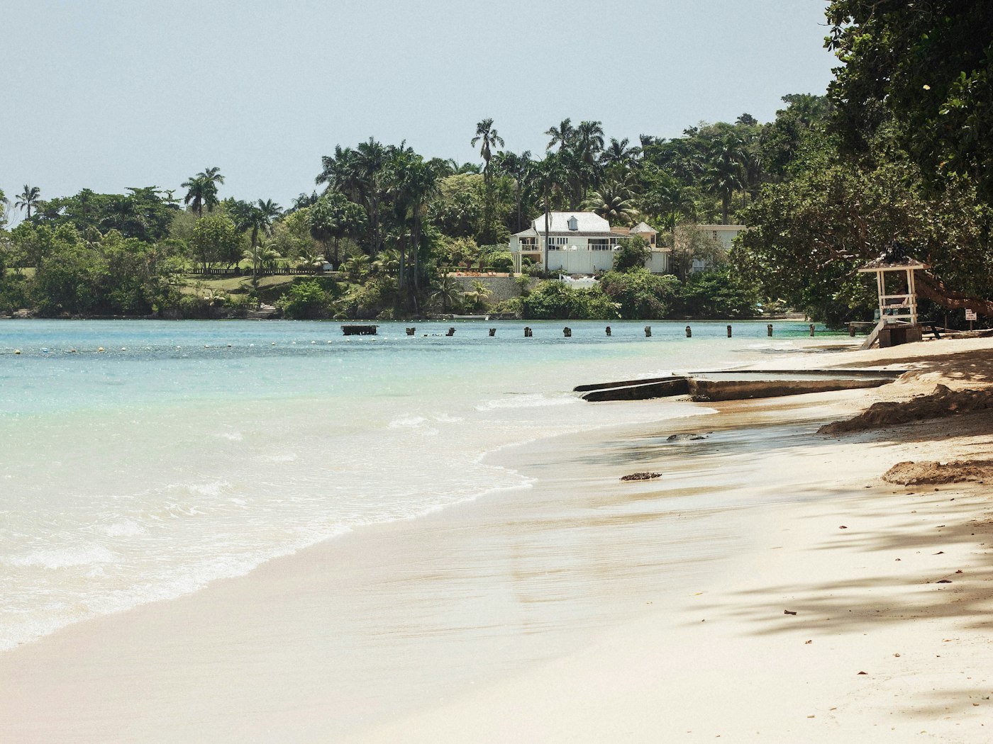 A quiet white-sand cove on Jamaica's north coast, fringed with palms.