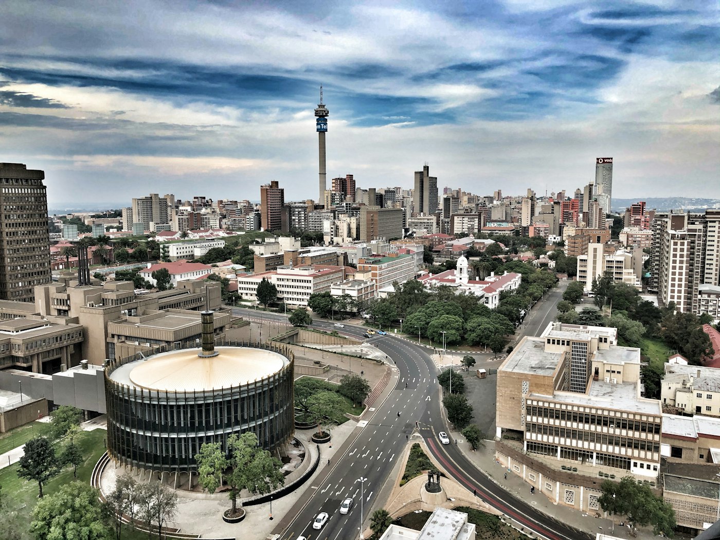 The Johannesburg skyline under dramatic cloud, the Hillbrow Tower rising at the centre.