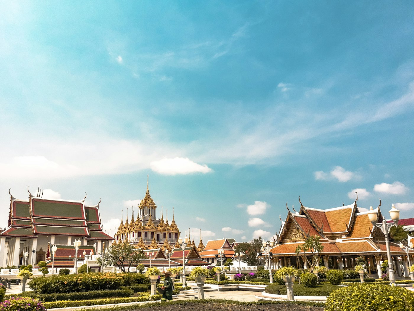 Gilded spires and tiered temple roofs in central Bangkok under a clear sky.