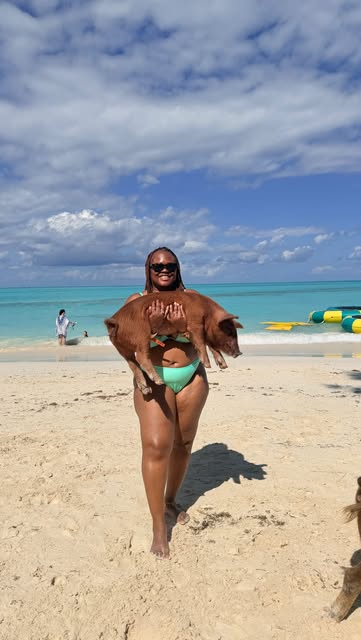 Temi on a Bahamian beach holding one of the Exuma swimming pigs.