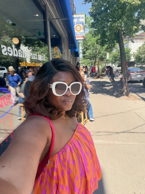 Temi in a bright orange and pink dress on a sunny Montreal street.