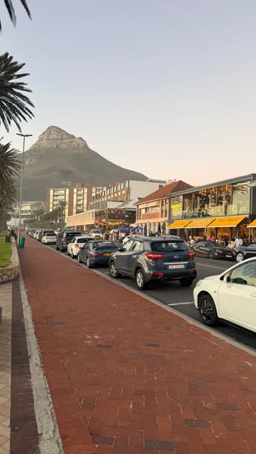 The Camps Bay strip in Cape Town at dusk, Lion's Head rising behind.