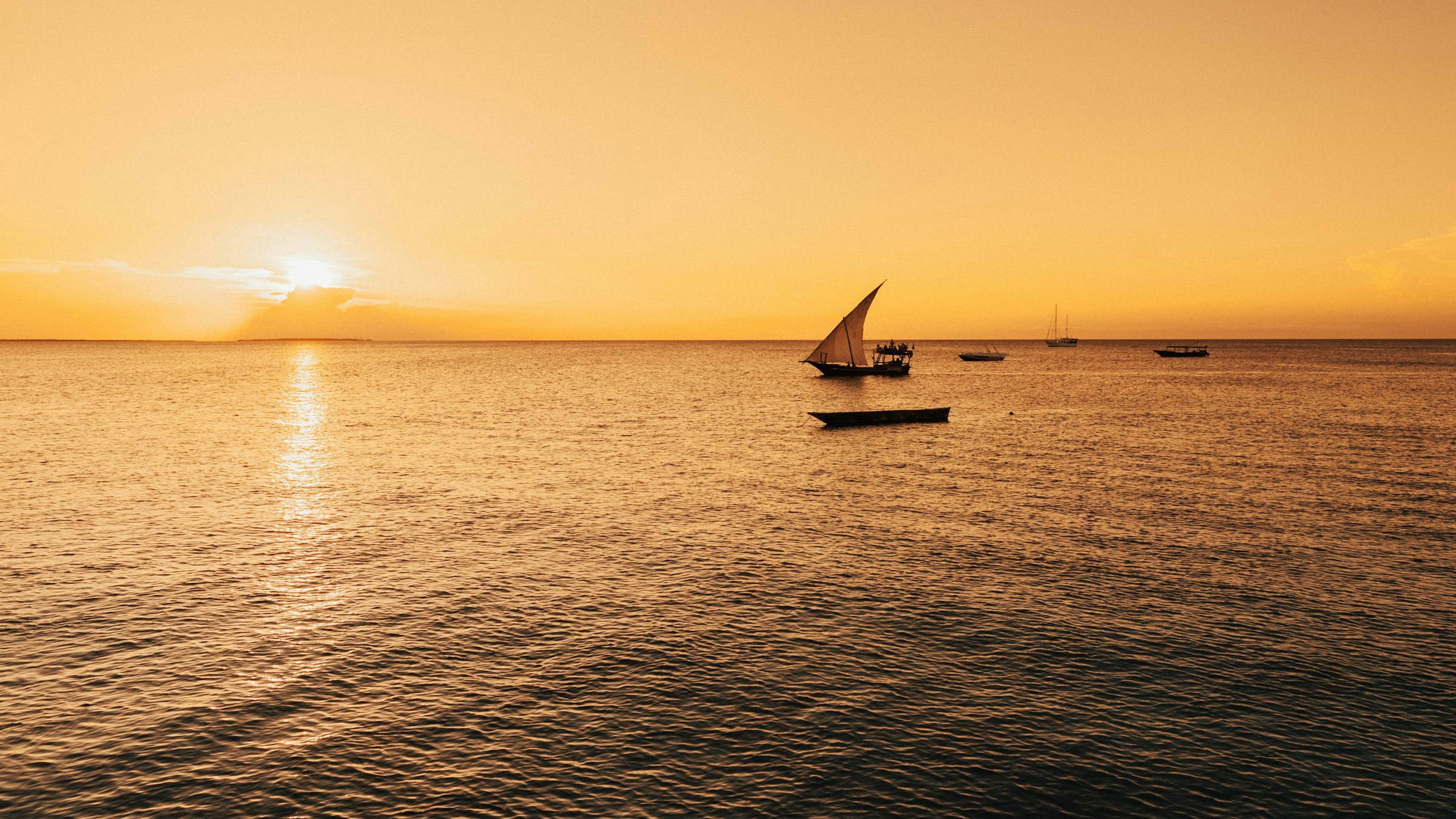 A sky turned entirely gold at sunset over calm open water.